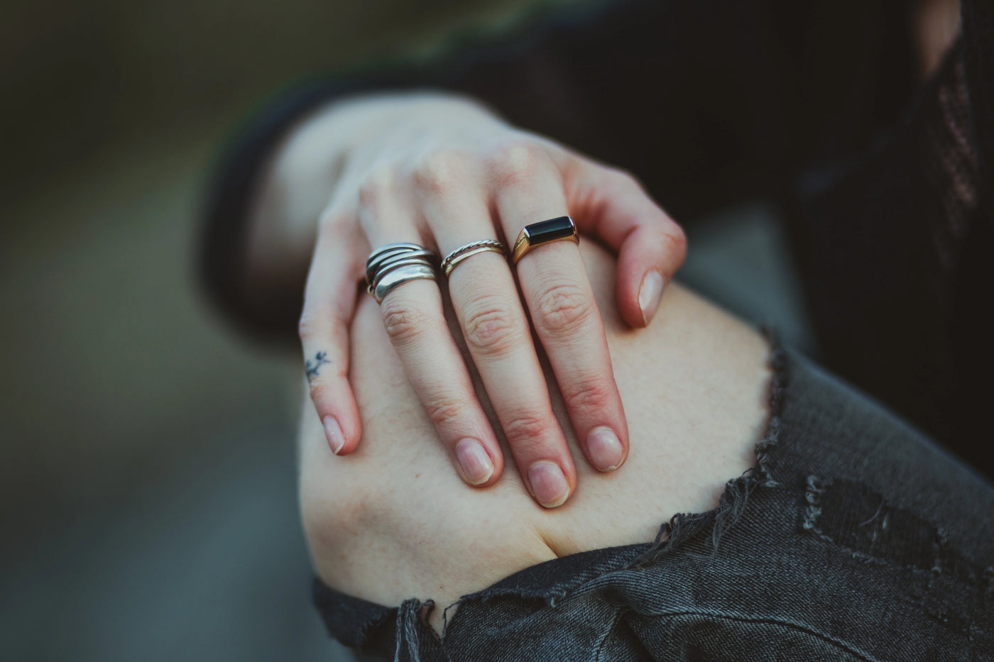 Hand on knee wearing multiple rings on hand.