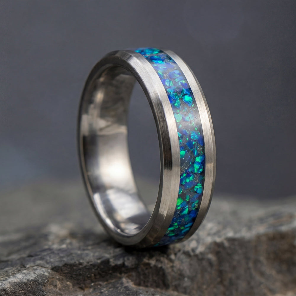 Silver ring with blue opal inlay on a dark stone surface